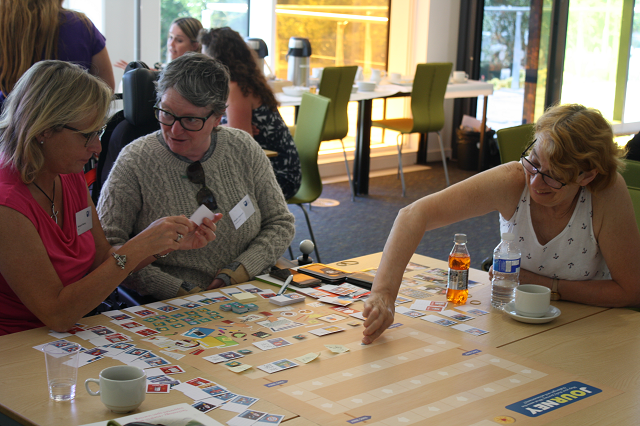 Three people creating a journey together using the Our Journey cards and poster